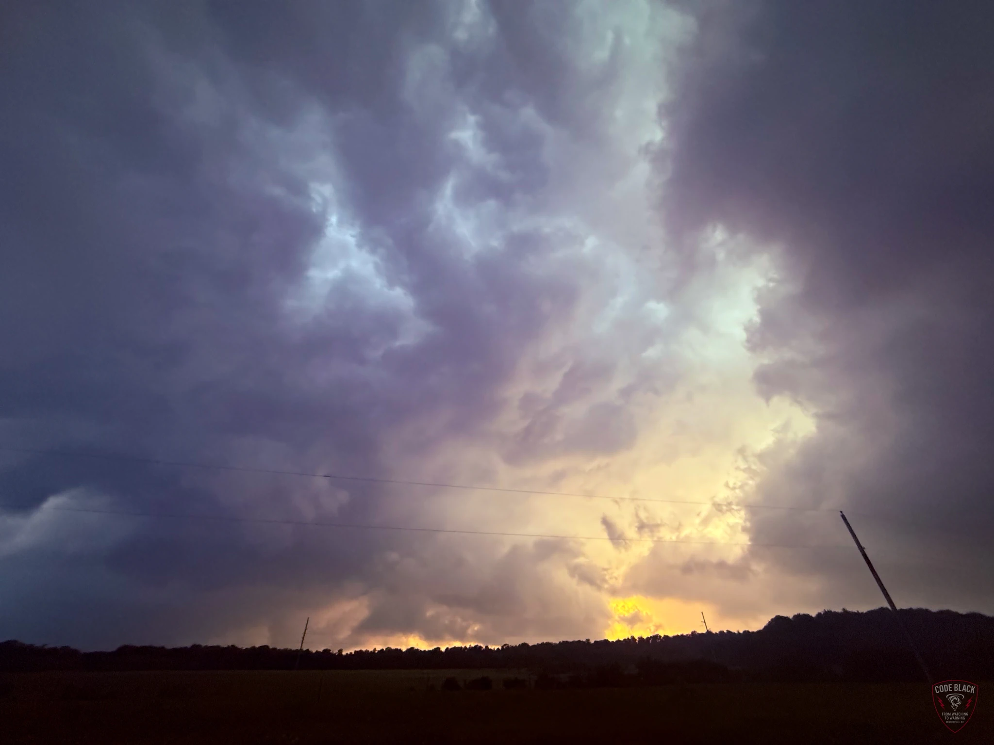 Gold evening light beneath layered storm clouds near Atoka, with the original Code Black watermark