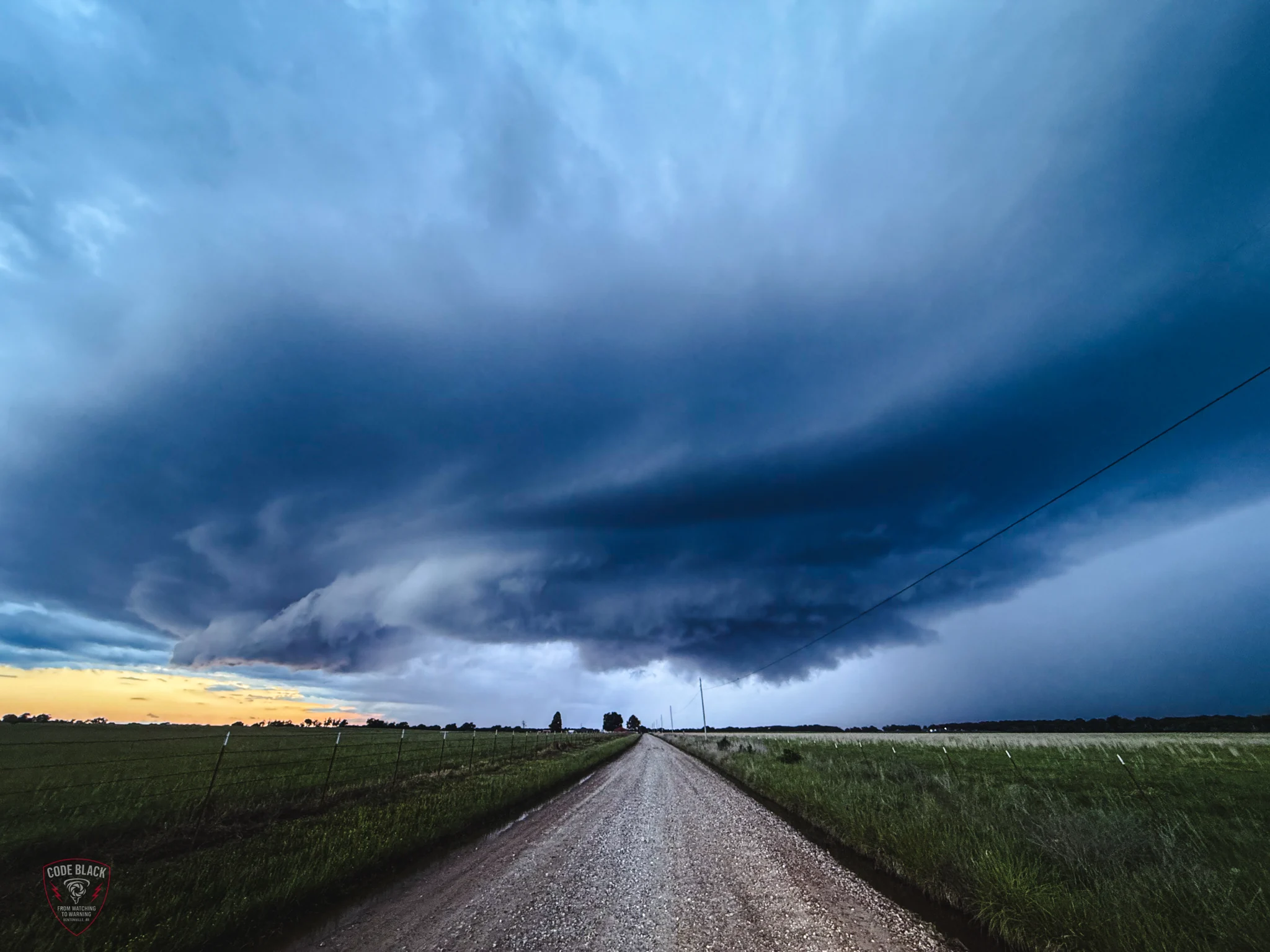 A gravel road beneath blue storm clouds