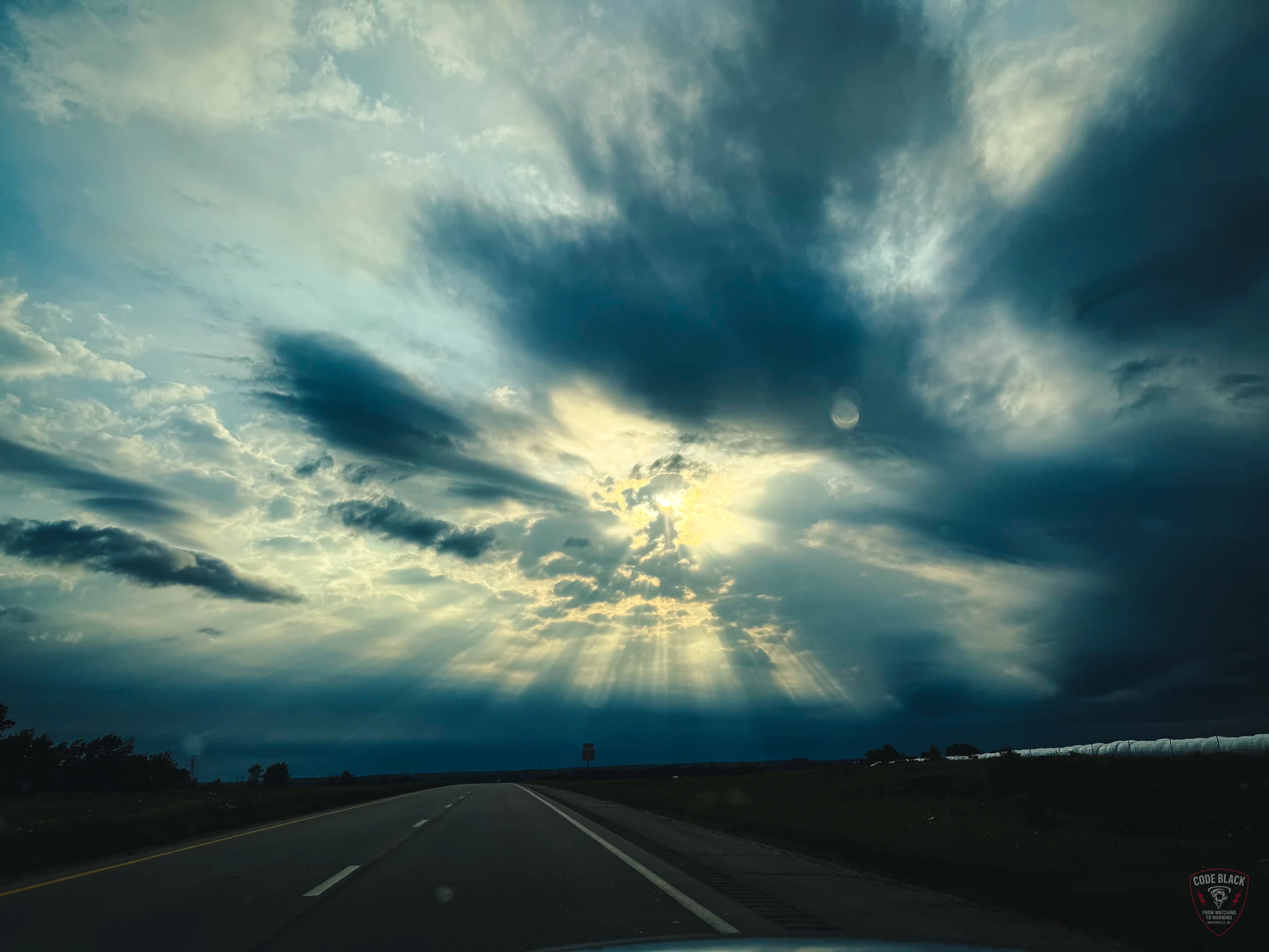 Sunlight breaking through clouds over a highway