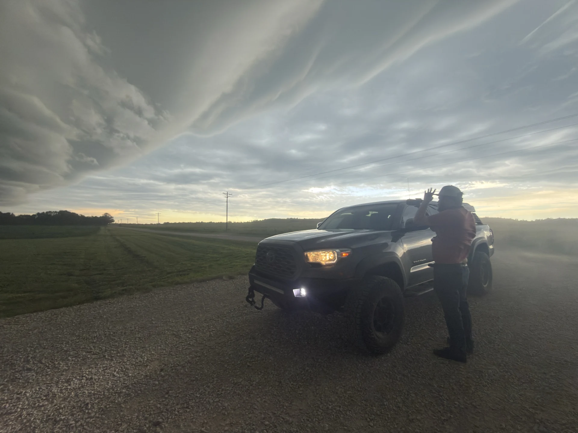 Nick beside the chase vehicle beneath a wide cloudy sky